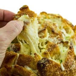 Pull apart three cheese garlic bread is a round sourdough loaf drizzled with garlic butter and stuffed with melting cheese. Crusty, and gooey hot bread made easy in under 30 minutes. #mustlovehomecooking