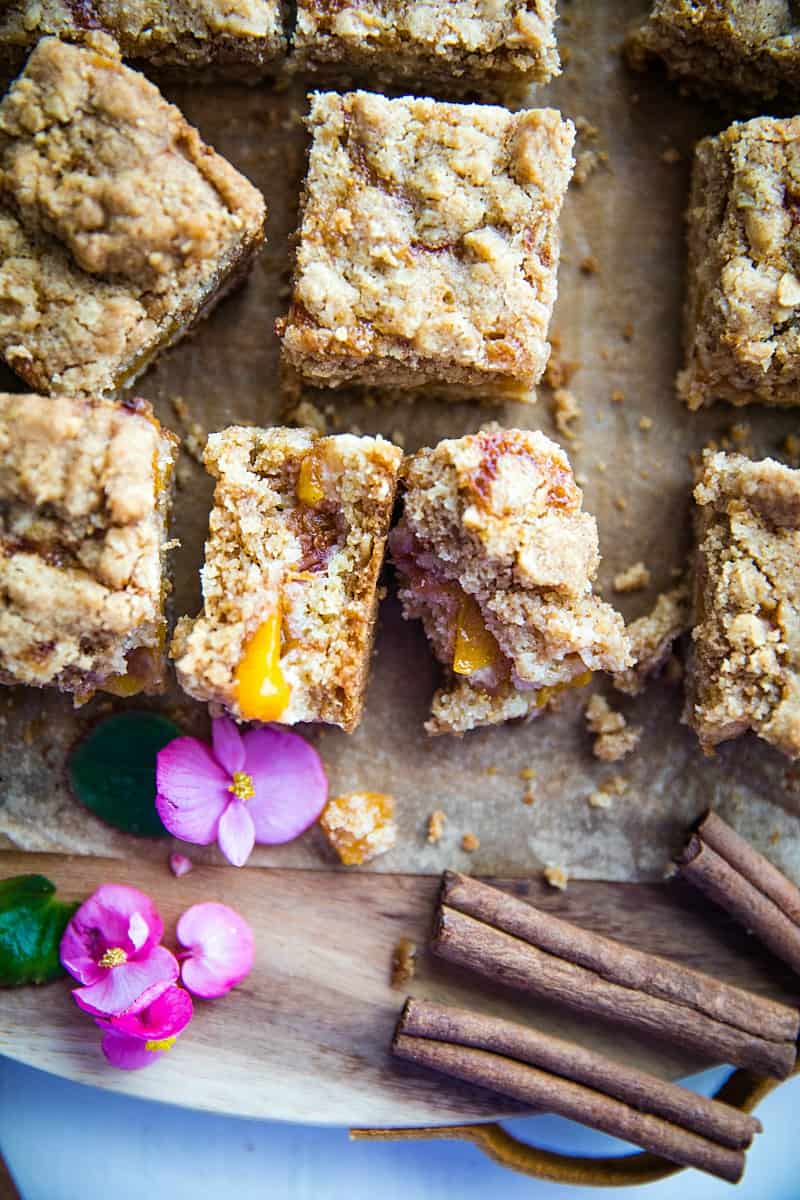 Buttery and decadent, these simple Cinnamon Spice Peach Crumb Bars with oats and spice are just in time for this seasonal fruit. #mustlovehomecooking