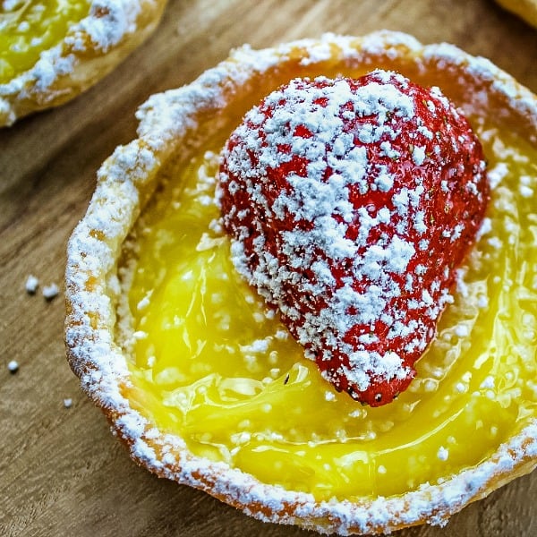 Cool, tangy and dotted with fresh strawberry this simple mini lemon tart dessert takes only 4 easy ingredients and no special pans to make them! #mustlovehomecooking