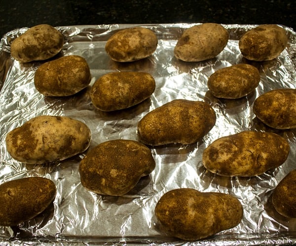 russet potatoes on foil lined baking sheet ready for the oven