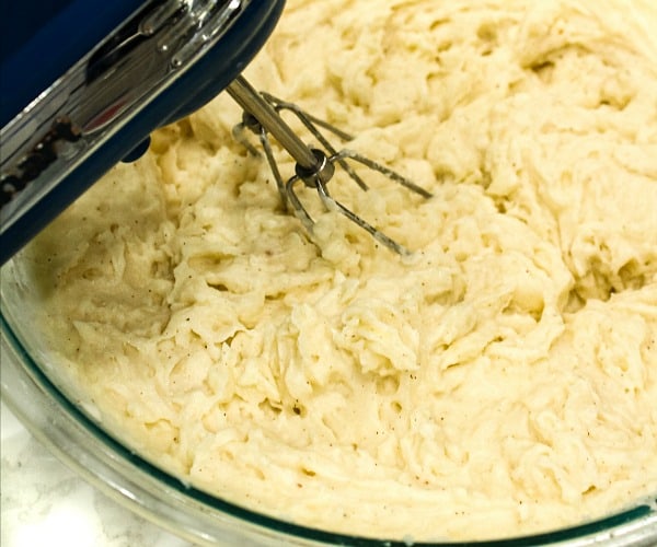 baked potatoes being whipped in glass bowl