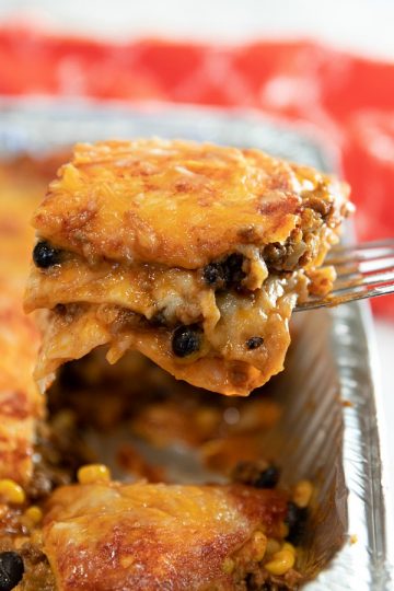 Easy Mexican Beef Lasagna - it's a Taco Tuesday favorite with layers of seasoned ground beef, tortillas, black beans, salsa and mounds of melted cheese. A freezer meal that's ready to just pop in the oven! #mustlovehomecooking