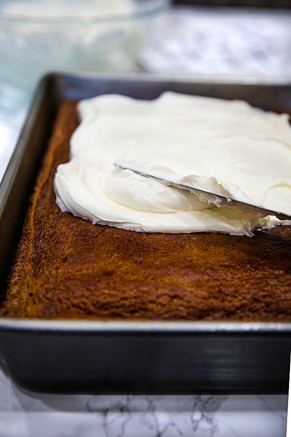 Cream cheese frosting spread on baked sheet cake