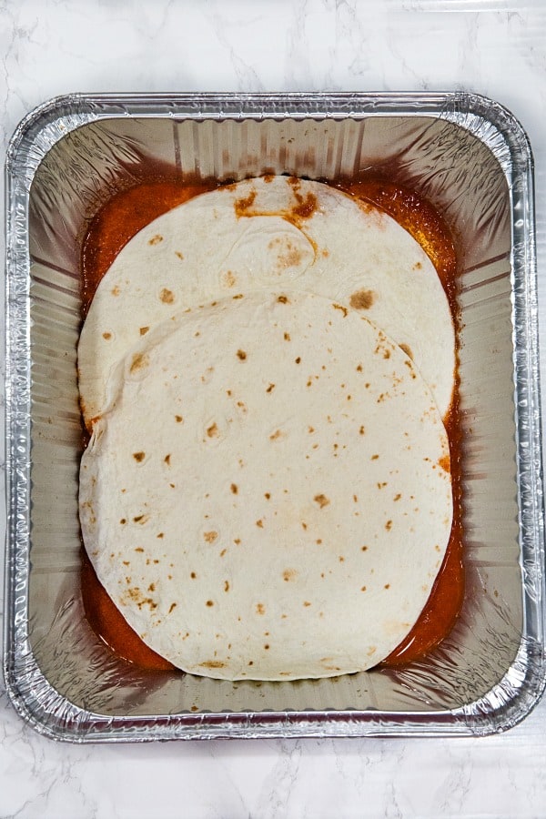 Layering mexican lasagna in foil pan for freezing.