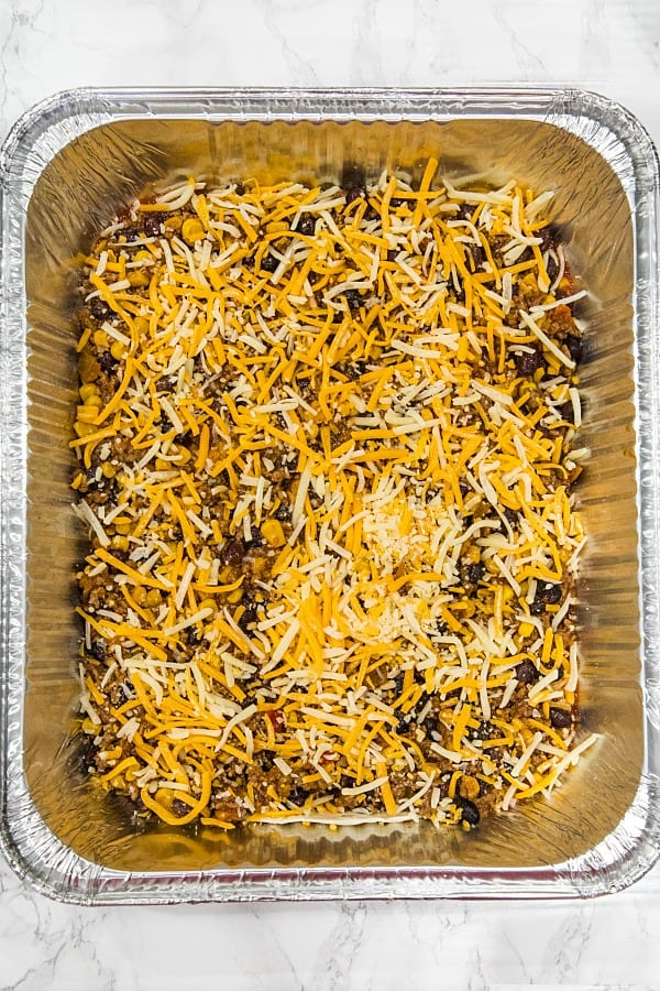 Layering mexican lasagna in foil pan for freezing.