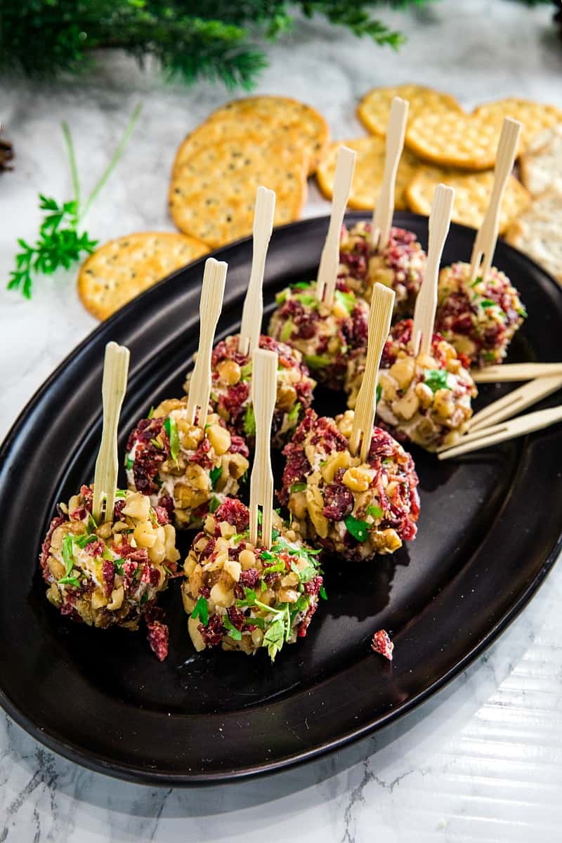 Festive bite size cheese balls take only minutes and are chock full of tangy goat cheese, cranberries and crunchy walnuts! #mustlovehomecooking