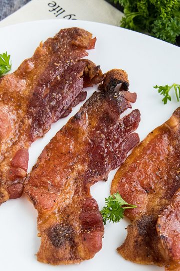 Spicy sweet bacon, with brown sugar and spices, cooked perfectly crisp and delicious in the oven. So easy with no mess or splatter! #mustlovehomecooking