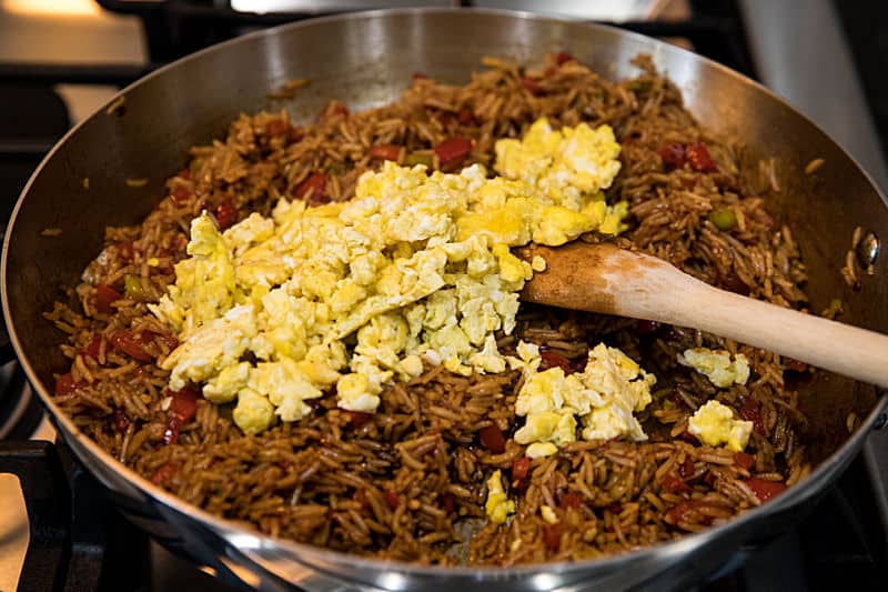 Adding cooked eggs to Peruvian Fried Rice in skillet