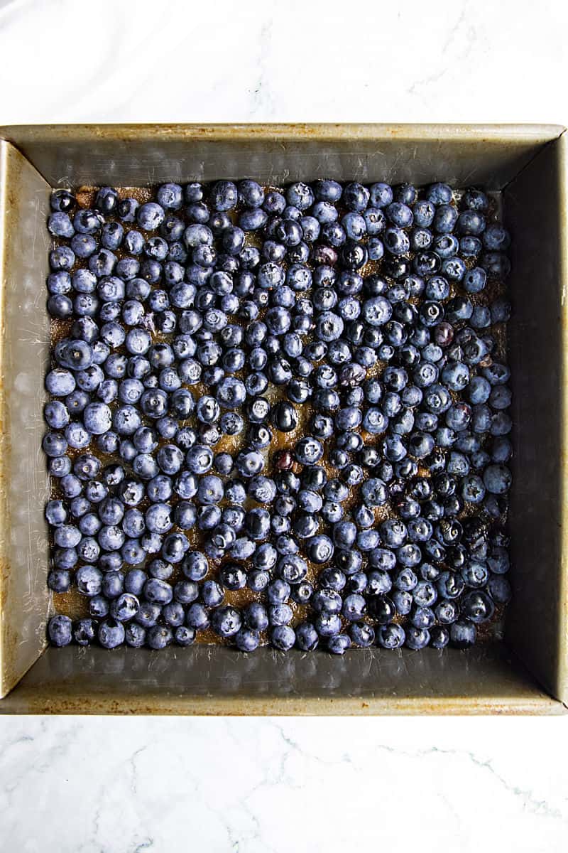 Blueberries butter and brown sugar in metal baking pan for blueberry upside down cake