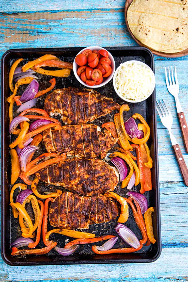 Classic chicken fajitas, with a twist, made easy on one sheet pan! An easy and delicious dinnertime favorite of juicy, adobo brushed chicken breasts, fresh bell pepper and onions all wrapped up in a soft flour tortilla. #mustlovehomecooking #mexicandinner #sheetpanrecipe