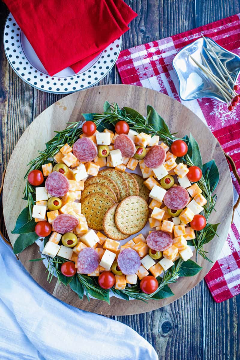 Cubed cheese, Italian sausage, stuffed olives and an abundance of seasonal herbs make this quick and easy show stopping appetizer wreath a favorite for holiday entertaining! #mustlovehomecooking