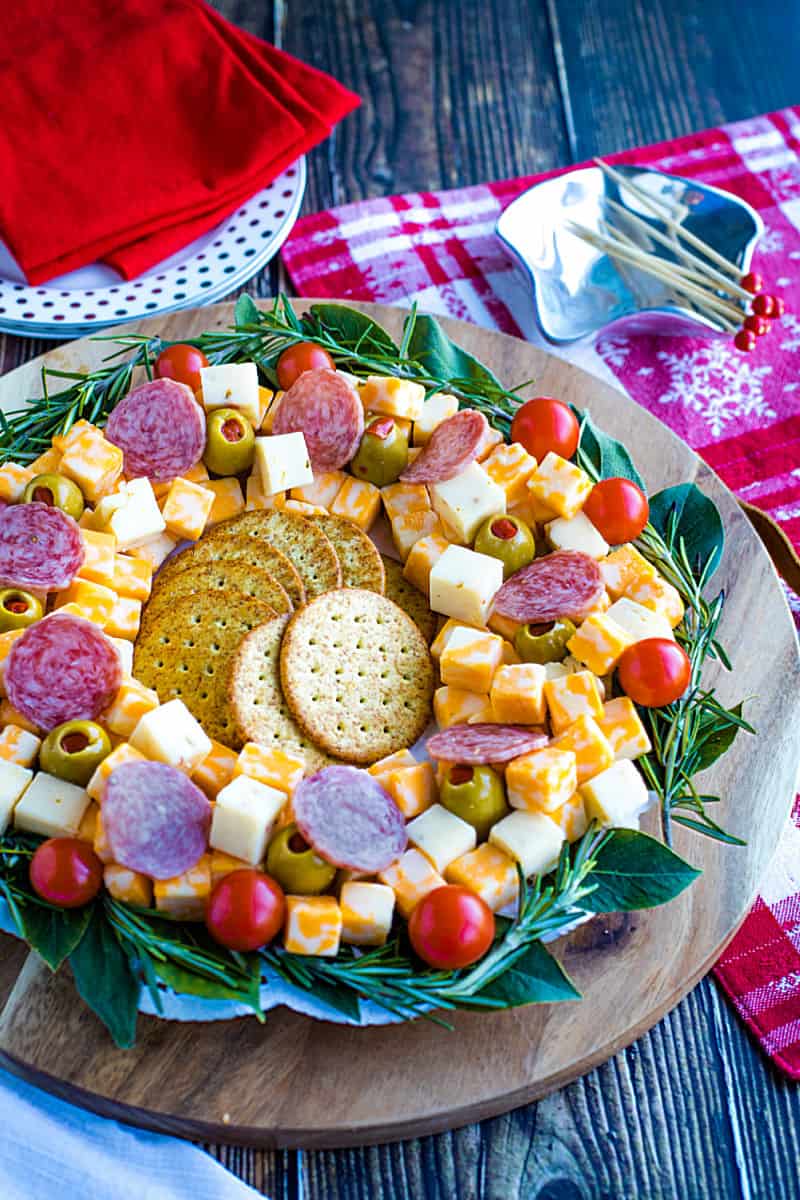 Cubed cheese, Italian sausage, stuffed olives and an abundance of seasonal herbs make this quick and easy show stopping appetizer wreath a favorite for holiday entertaining! #mustlovehomecooking