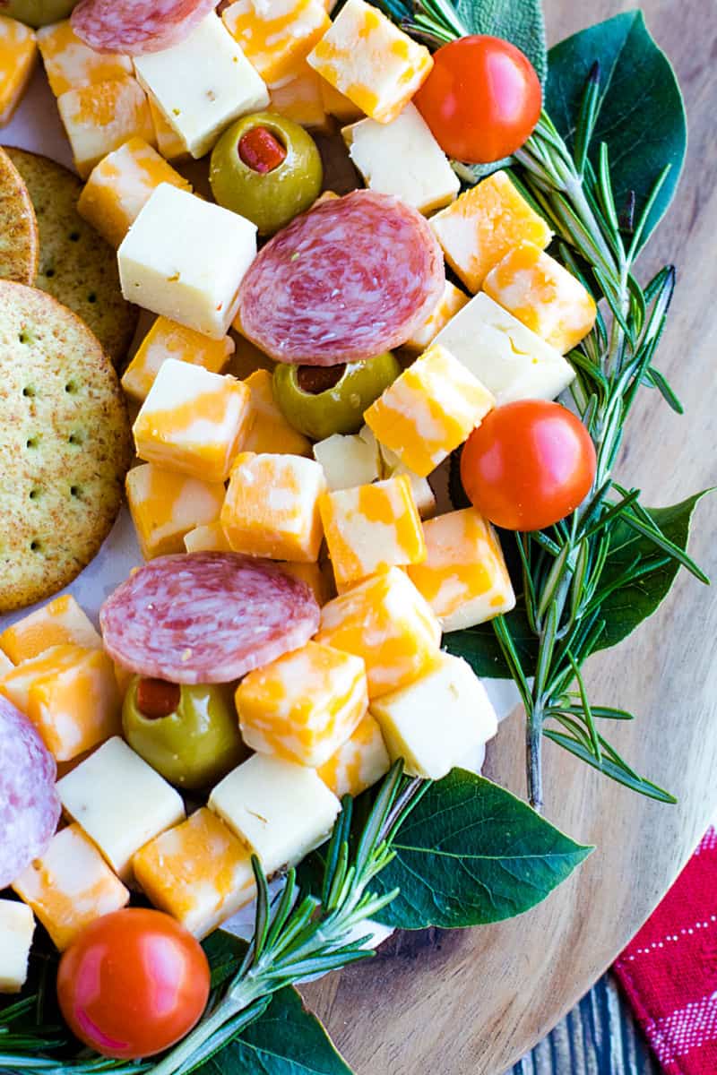 Cubed cheese, Italian sausage, stuffed olives and an abundance of seasonal herbs make this quick and easy show stopping appetizer wreath a favorite for holiday entertaining! #mustlovehomecooking