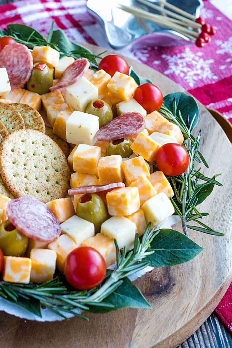 Cubed cheese, Italian sausage, stuffed olives and an abundance of seasonal herbs make this quick and easy show stopping appetizer wreath a favorite for holiday entertaining! #mustlovehomecooking