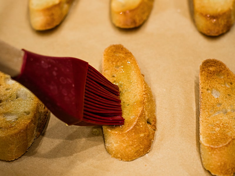 brushing olive oil on toasted crostini